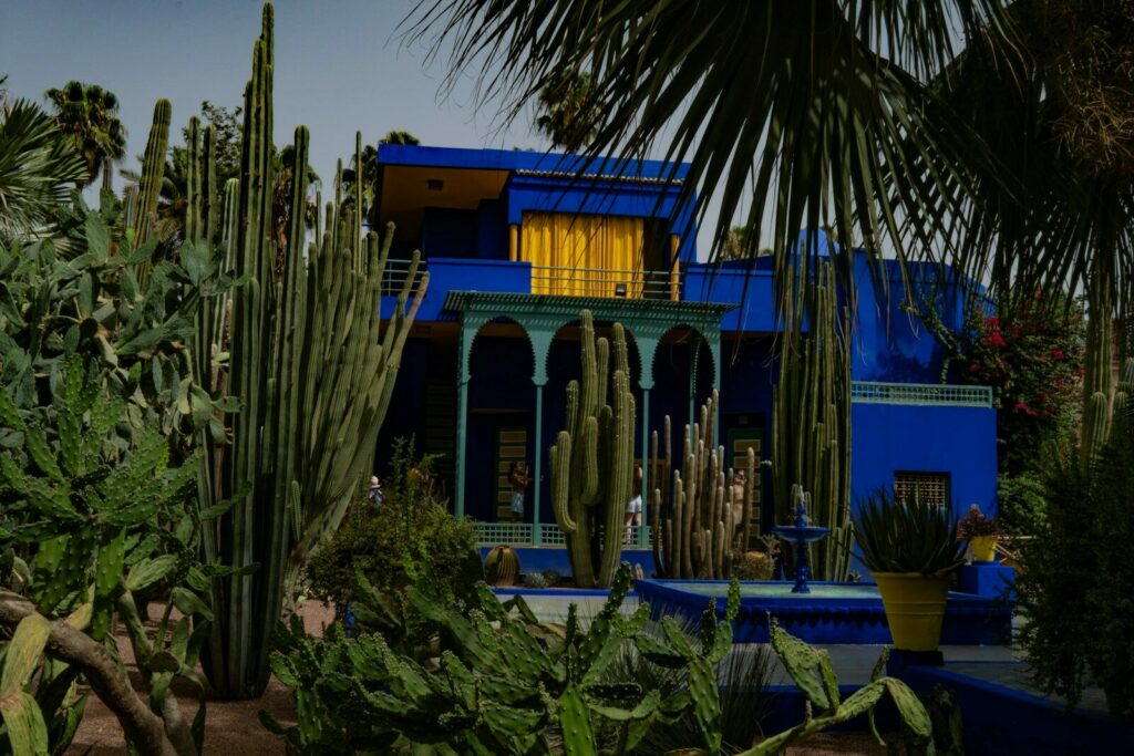 Vibrant blue building surrounded by cacti and palm trees